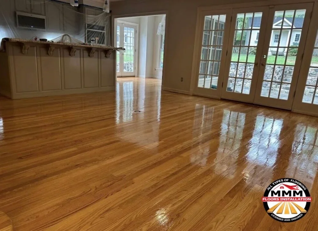Polished hardwood flooring with glossy finish in open room with cabinetry and glass doors
