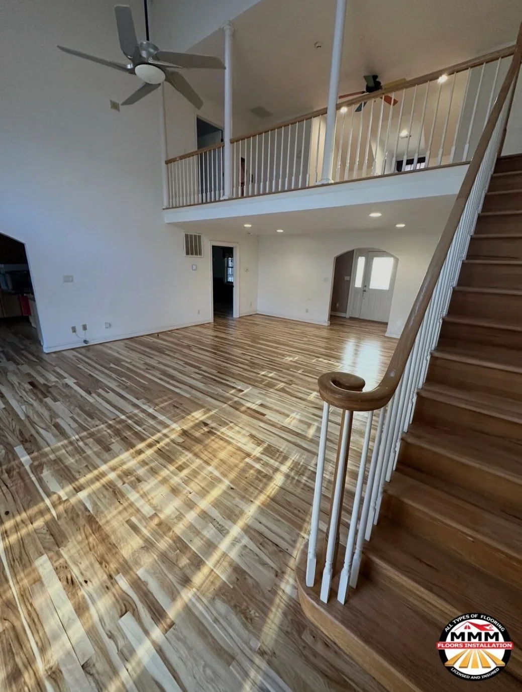 Herringbone hardwood flooring in open two-story space with white railings and recessed lighting