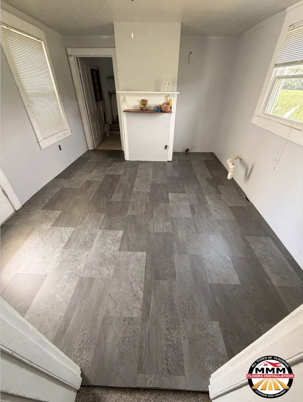 Gray luxury vinyl plank flooring in herringbone pattern, newly installed in kitchen and living area