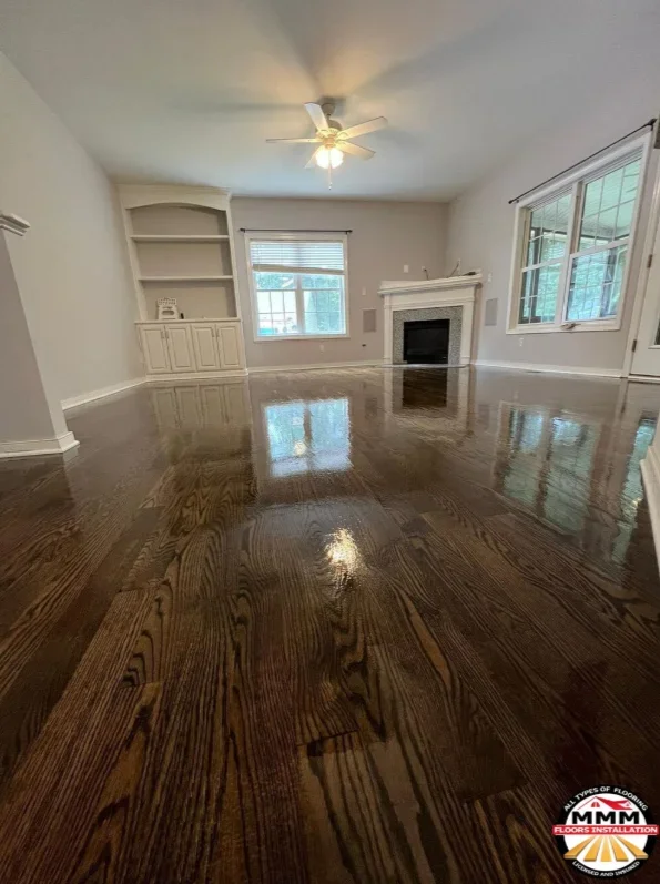 Dark stained hardwood flooring with high-gloss finish in living room with fireplace and built-ins