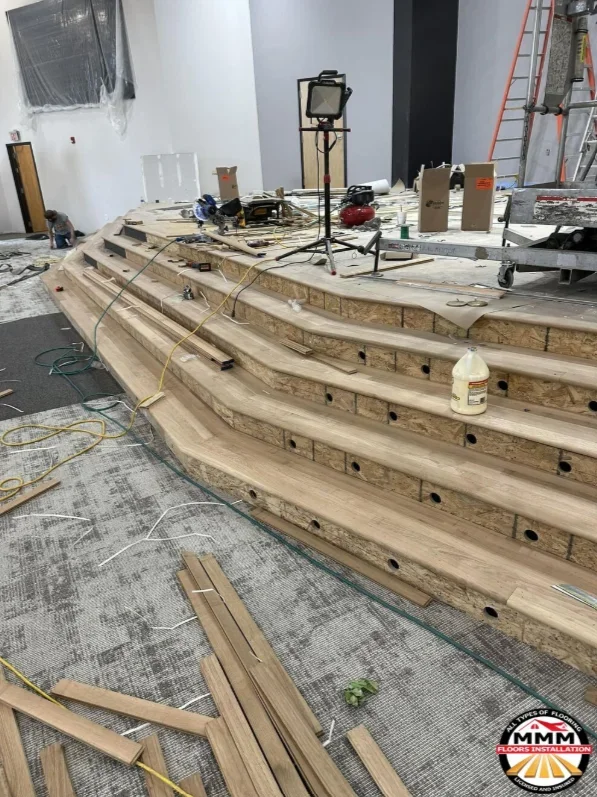 Curved hardwood flooring planks with pre-drilled holes during installation in interior space