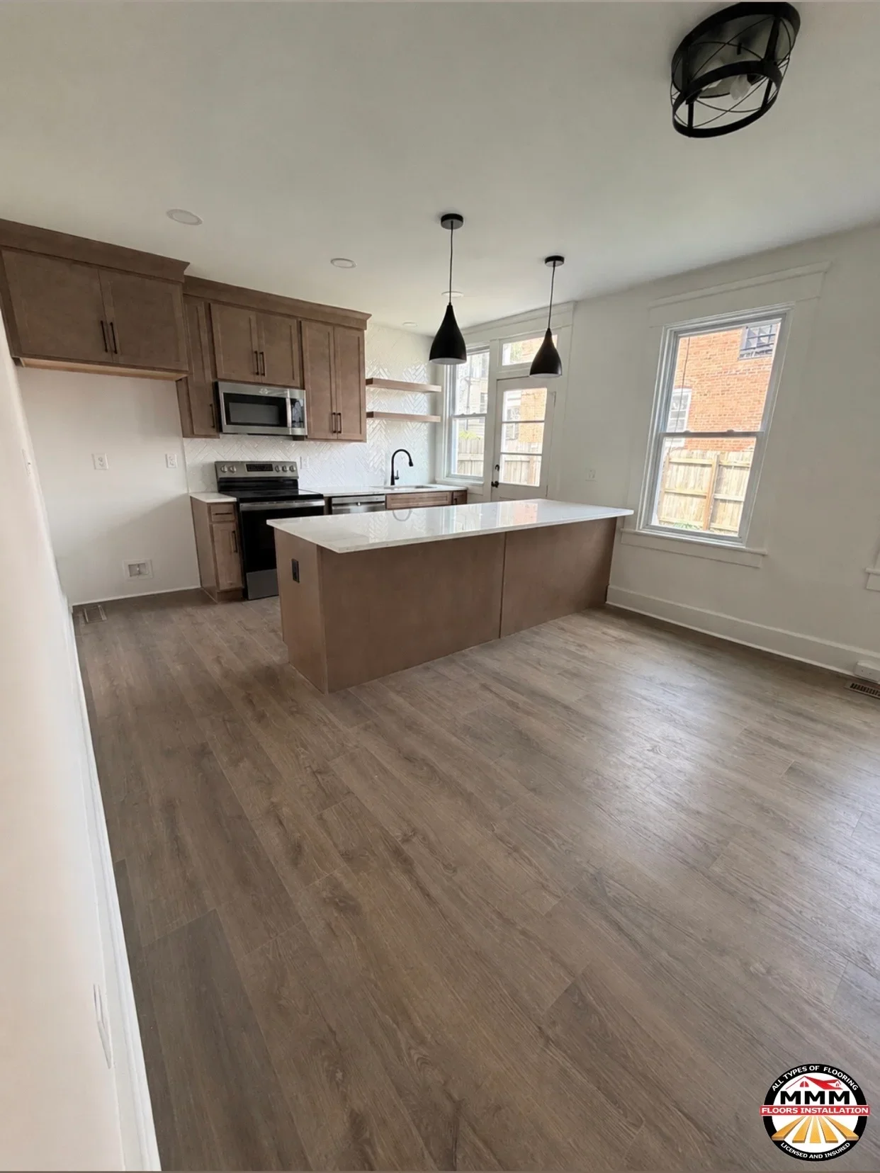 Luxury vinyl plank flooring in kitchen with brown cabinets and white island countertop