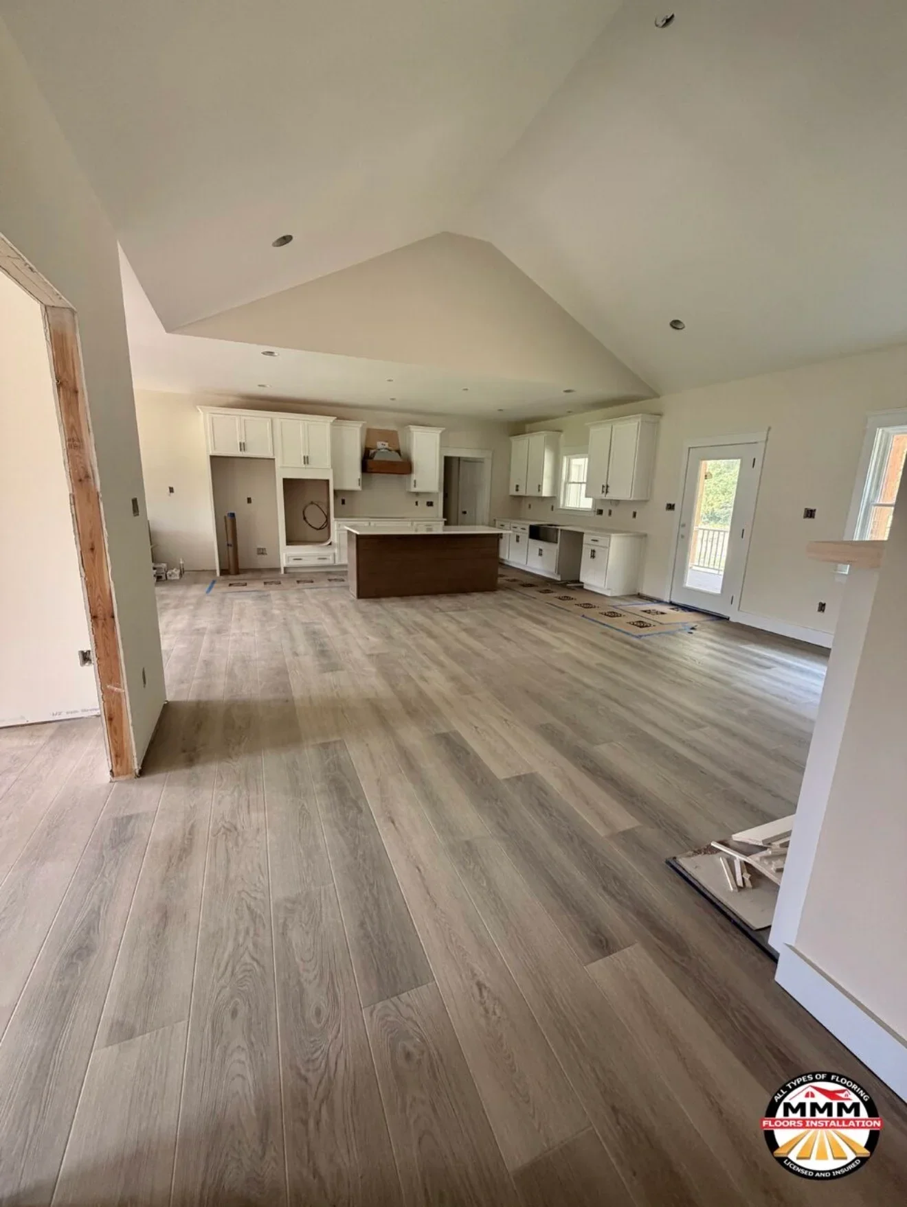Gray wood-look vinyl plank flooring installed in open kitchen and living area with white cabinetry and island