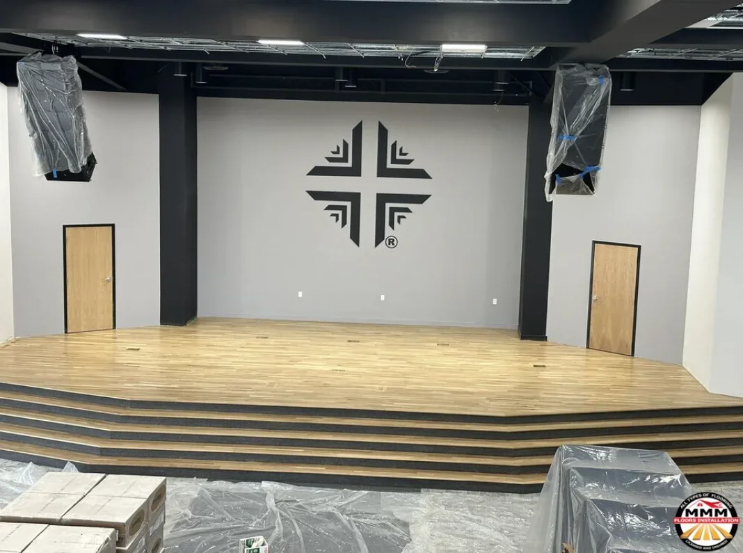 Hardwood stage platform with striped inlay detail, wood doors, and black support columns