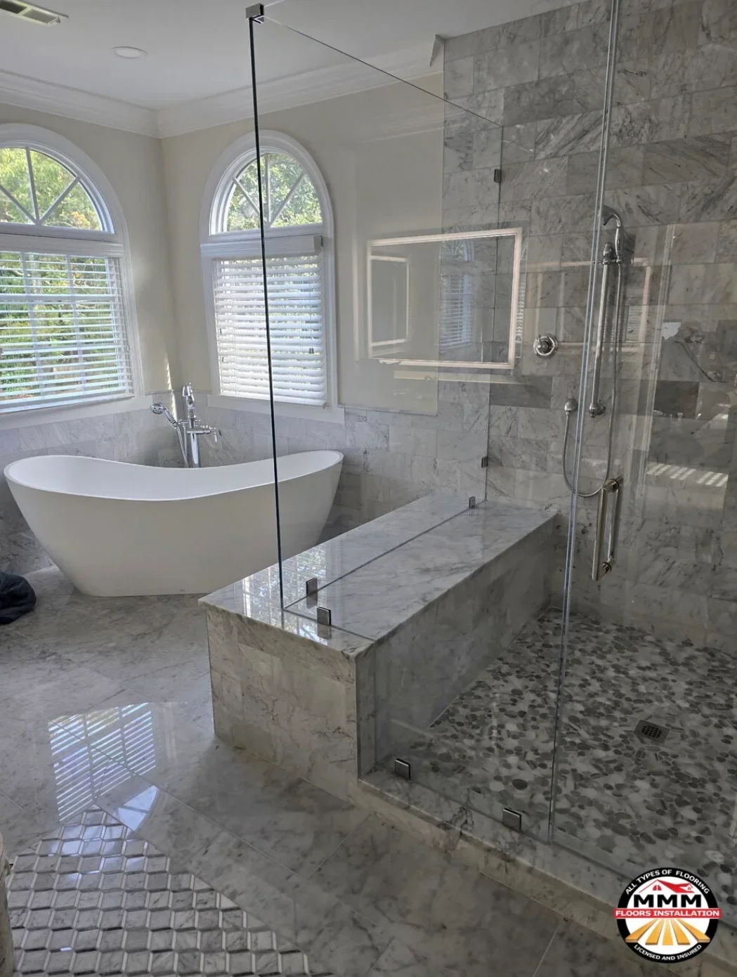 Marble tile bathroom with freestanding tub, walk-in shower with glass enclosure, and marble flooring