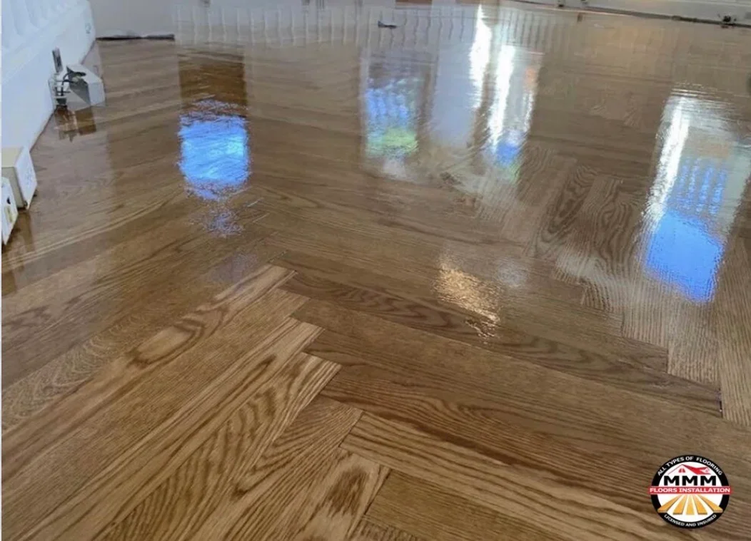 Herringbone pattern hardwood floor installation with oak wood and glossy finish